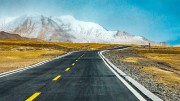 雪山下草原上的公路景观图片
